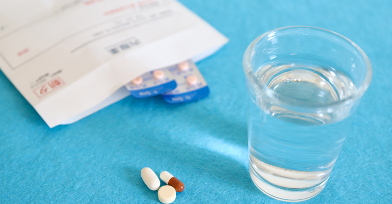 Medikamenten und Wasserglas auf blauer Fläche