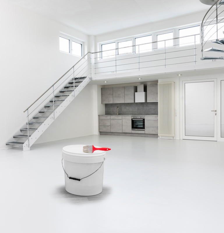 ein Kübel mit weißer Farbe steht in einem weiß ausgemalten großen leeren Wohnraum